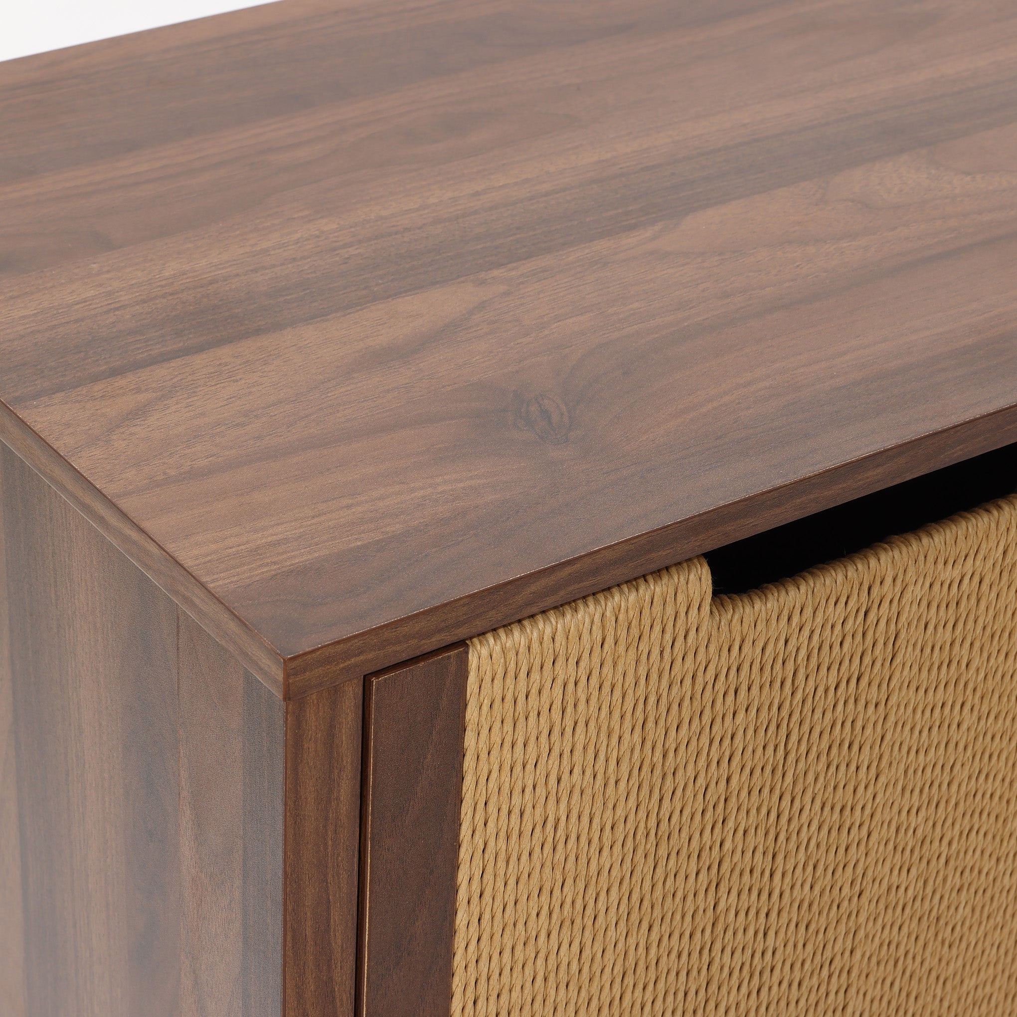 A close-up of a wood storage cabinet with a smooth finish and a woven beige basket partially visible in one of its compartments.
