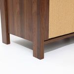 Close-up of the bottom corner of a wood storage cabinet with vertical legs and a textured beige side panel.