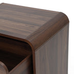 Close-up view of the top corner of a walnut nightstand with a visible drawer ,rounded edges.