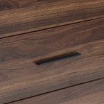 A close-up of a wood storage chest drawer with a dark, horizontal metal handle.