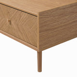 Close-up view of a wood coffee table with storage, featuring a drawer, angled corner detail, cylindrical metal leg.