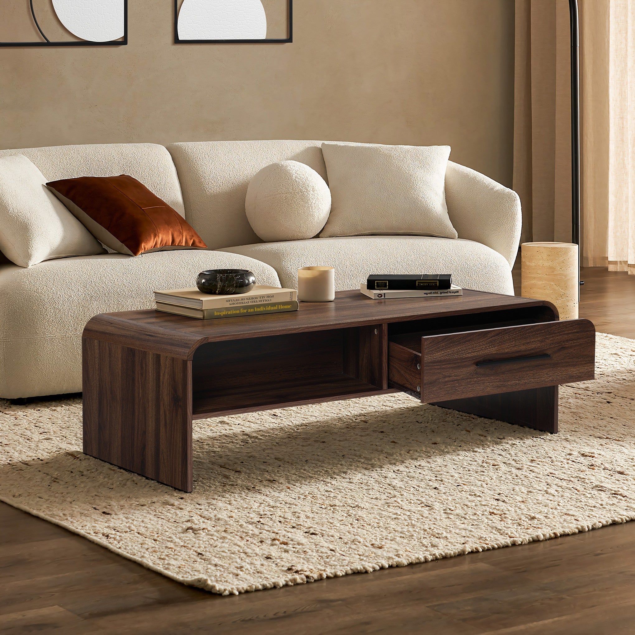 A wooden coffee table with dual-sided storage, books, and a candle on a light woven rug.