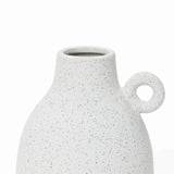 A speckled white ceramic vase with a round handle on one side, featuring a wide opening at the top and showcasing a vintage-inspired design.