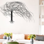 A modern living room with a tan sofa, white furry pillow, vases with flowers, and a striking handcrafted metal tree wall decor on a white wall.