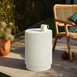 A ceramic mug rests on a versatile table with a textured ivory white surface next to a wooden chair on a sunny patio. In the background, a potted plant and a basketball add life to the scene.