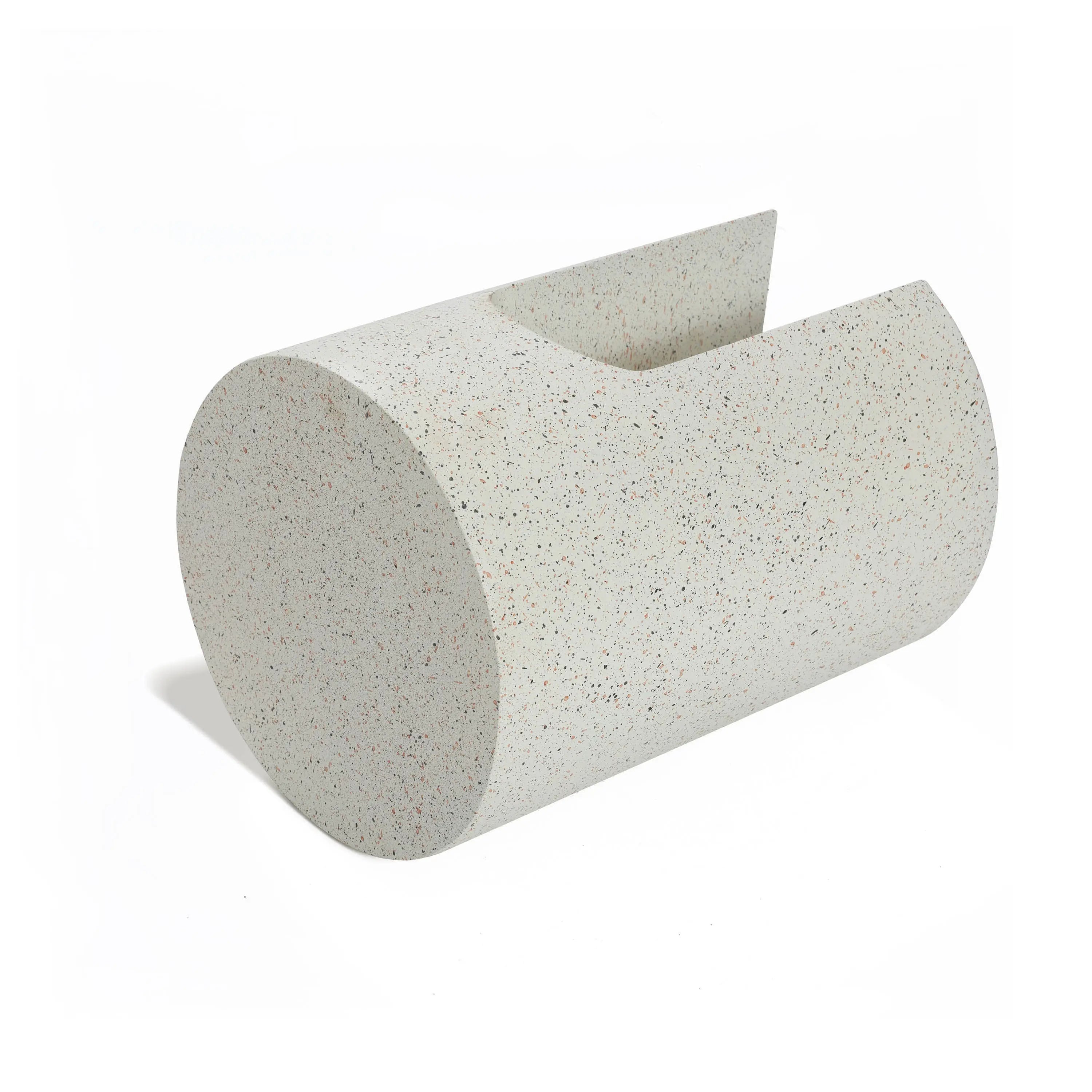 A speckled, ivory white cylindrical object with a slanted top and U-shaped design, resembling a minimalist sculpture, stands elegantly on a white background.