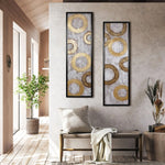 A modern interior features two framed abstract circle paintings enhancing the wall decor, a cozy bench with a pillow and blanket, a potted tree, and a decorative vase with dried plants. Subtle touches of gold metal design add elegance to this harmonious home decor setup.