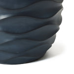 Wavy textured dark blue pot planter with a matte finish made from durable magnesium oxide, partially visible against a white background.