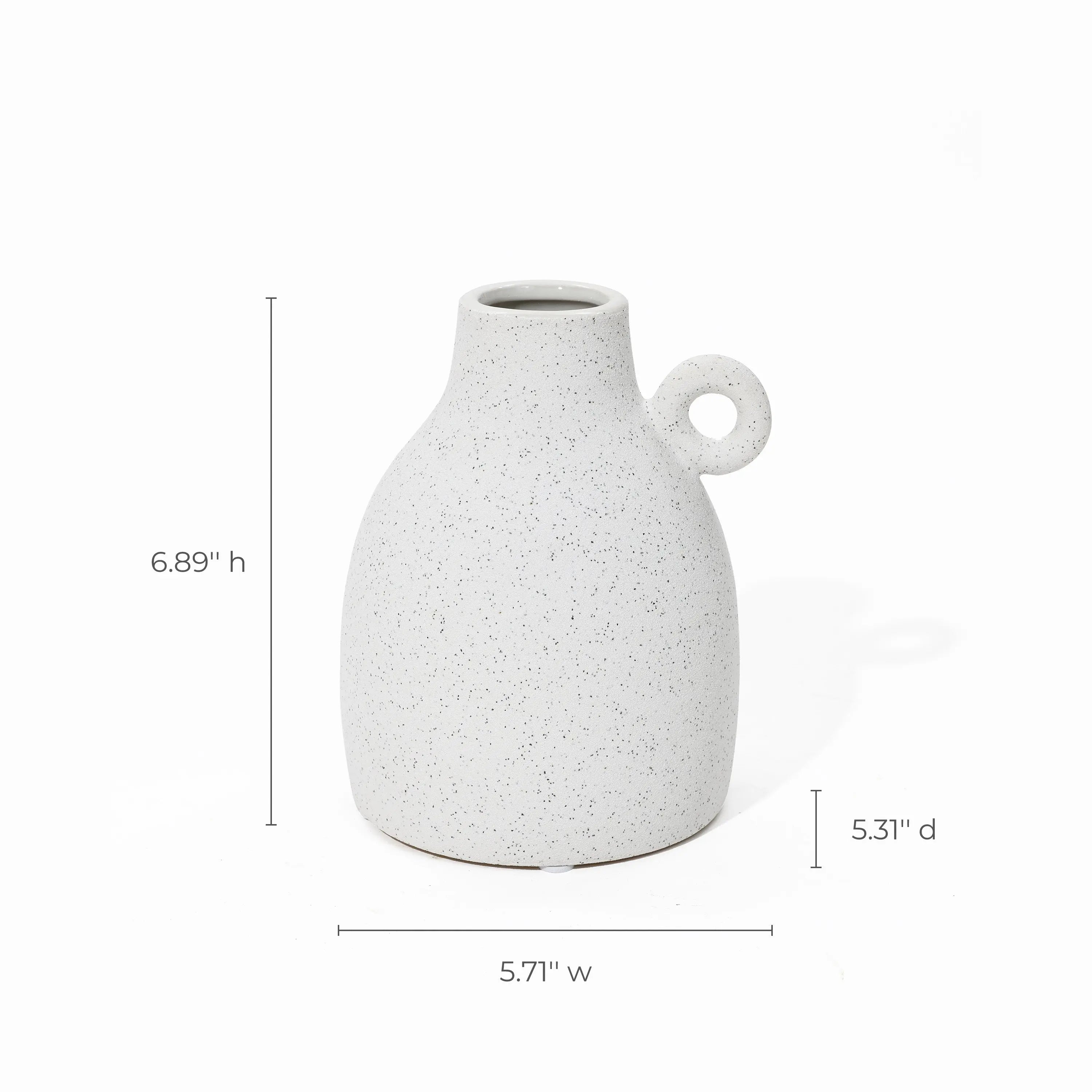 With its vintage-inspired design, this white speckled ceramic jug features a classic loop handle. Dimensions: 6.89 inches high, 5.31 inches deep, 5.71 inches wide—perfect as a charming accent piece or terracotta vase lookalike for any space.