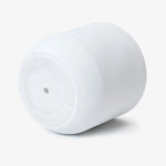 A white, cylindrical plastic object with a flat bottom and a single hole in the center is positioned against a plain white background, showcasing its minimalist design as a contemporary planter.
