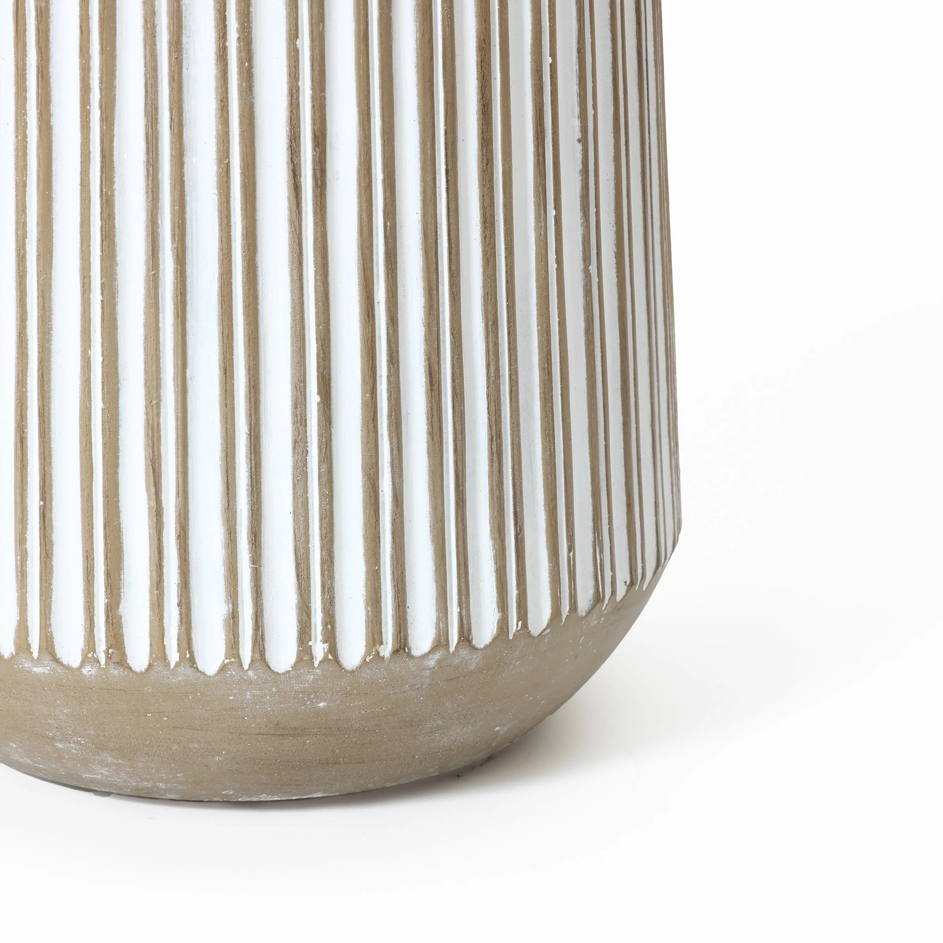 Close-up of a beige and white ceramic vase with vertical ribbed texture, resembling a striped planter, partially visible against a white background.