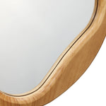 Close-up of an oval mirror with a natural wooden frame, displaying smooth curves and a light finish. This versatile accent piece effortlessly complements any space with its elegant design.