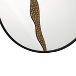 Close-up of a round wall mirror featuring an artistic design with a wavy bronze textured pattern running vertically down the center. The frame is black, offering a sleek touch to this modern decoration.