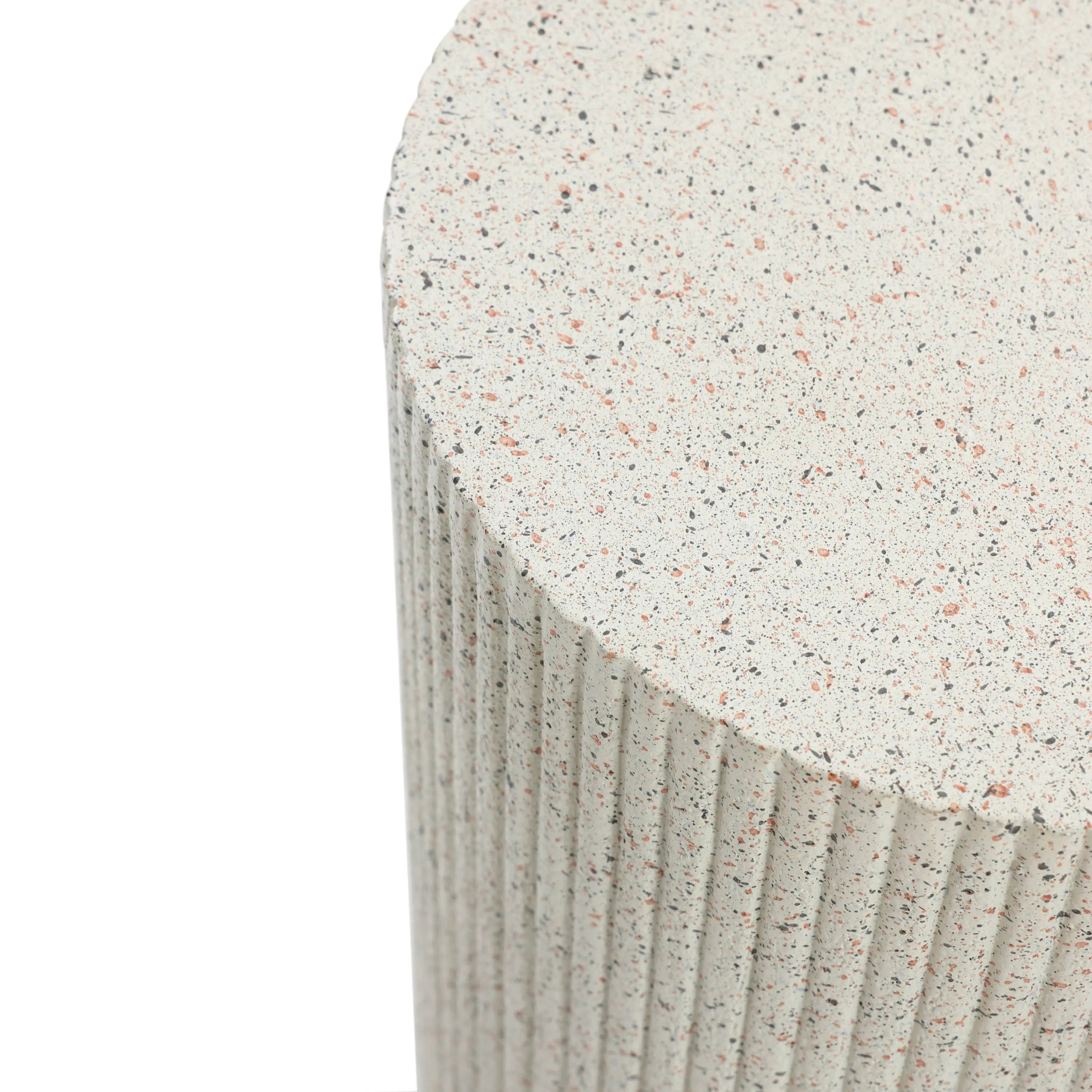 Close-up of a textured, cylindrical ivory white side table with a speckled surface and vertical ridges, crafted from durable cement material.