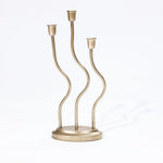 An elegant candle holder with three wavy, vertical stems rises gracefully from the round base, embodying a sophisticated touch of home decor artistry against a white background.