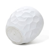 A textured white ceramic bowl, reminiscent of a geometric pot planter, turned upside down on a white surface.