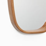 A close-up of a modern wall mirror with a handcrafted rubberwood frame on a sleek white wall.