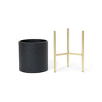 A textured black durable iron planter paired with a gold metal stand exudes a contemporary modern style.