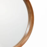 Close-up view of a wooden round wall mirror with a natural wood finish against a white background.