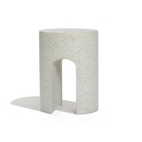 A white, cylindrical stool with a speckled pattern and a U-shaped cutout at the bottom sits elegantly against a plain background, perfect as an outdoor side table crafted from ivory white cement.