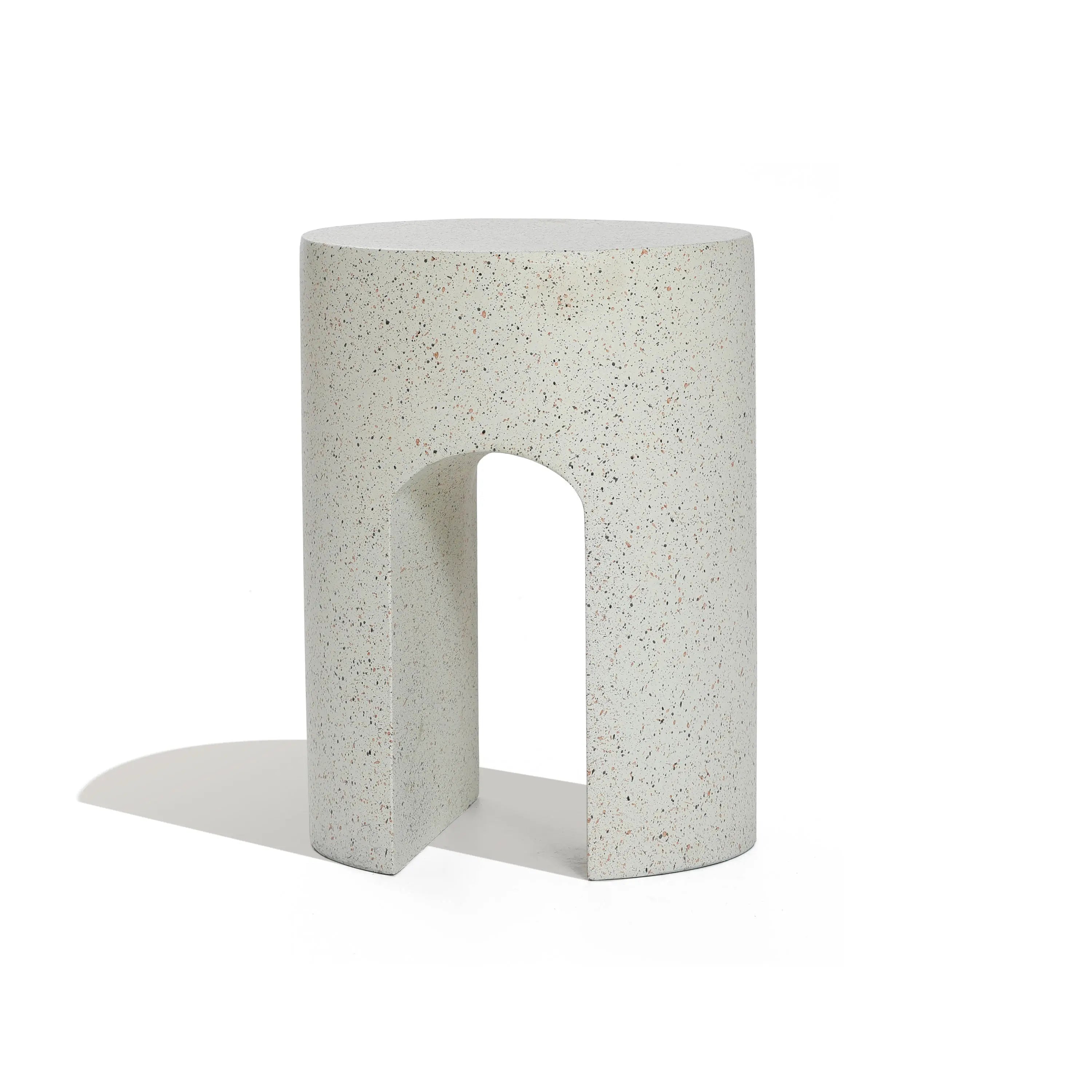 A white, cylindrical stool with a speckled pattern and a U-shaped cutout at the bottom sits elegantly against a plain background, perfect as an outdoor side table crafted from ivory white cement.
