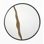 A round wall mirror with a black frame and an artistic design, featuring a wavy bronze accent that divides the surface vertically, perfect for modern decoration.