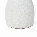 Close-up of a speckled, matte white ceramic surface with a rounded base on a white background, reminiscent of a vintage-inspired design.