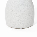 Close-up of a speckled, matte white ceramic surface with a rounded base on a white background, reminiscent of a vintage-inspired design.