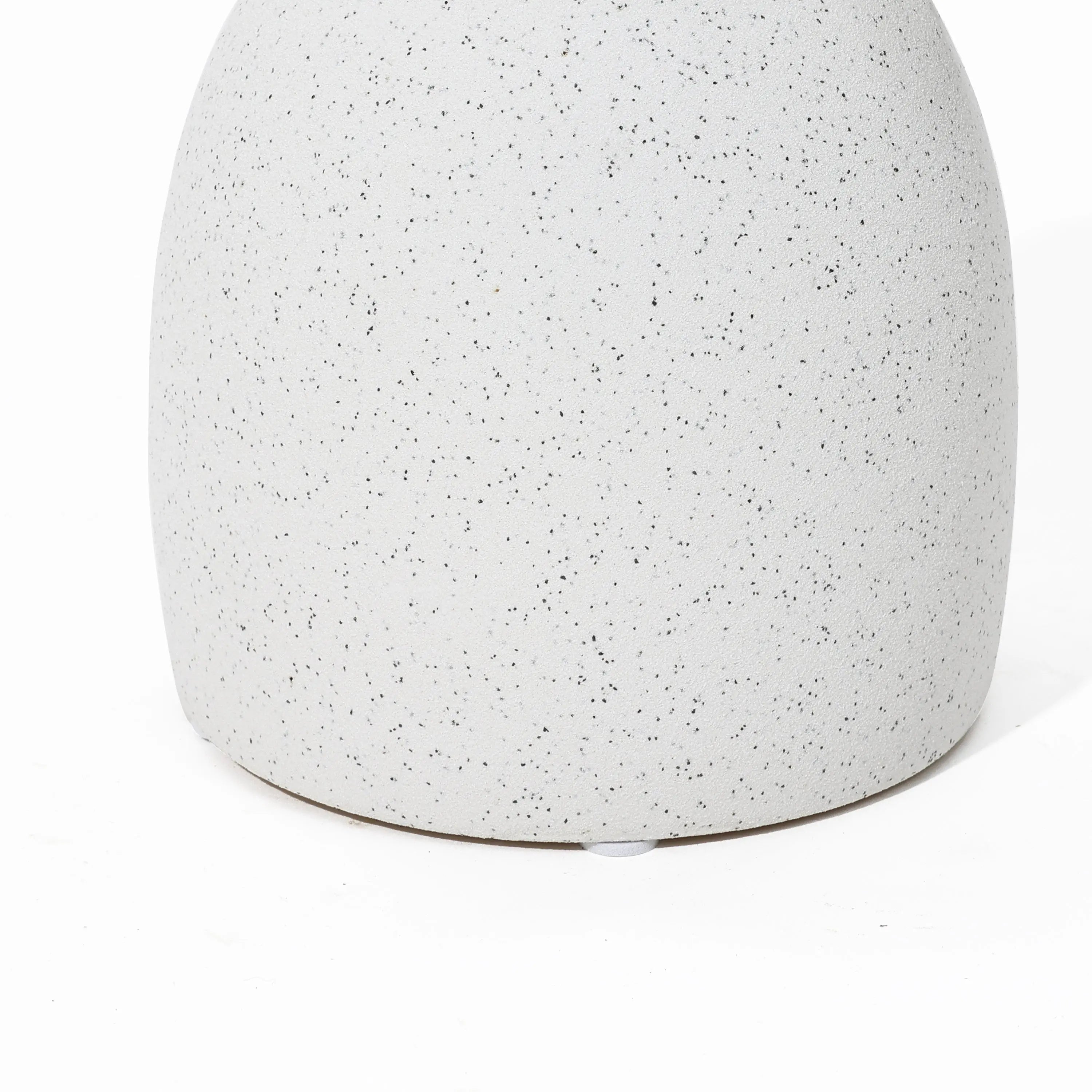 Close-up of a speckled, matte white ceramic surface with a rounded base on a white background, reminiscent of a vintage-inspired design.