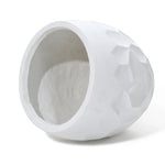 White, textured geometric vase, crafted from durable magnesium oxide material, lays on its side with an open top, showcasing a smooth interior perfect for both indoor and outdoor use.