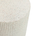 Close-up of a textured cylindrical surface reminiscent of an ivory white side table with vertical grooves and a speckled pattern in shades of beige, black, and pink.