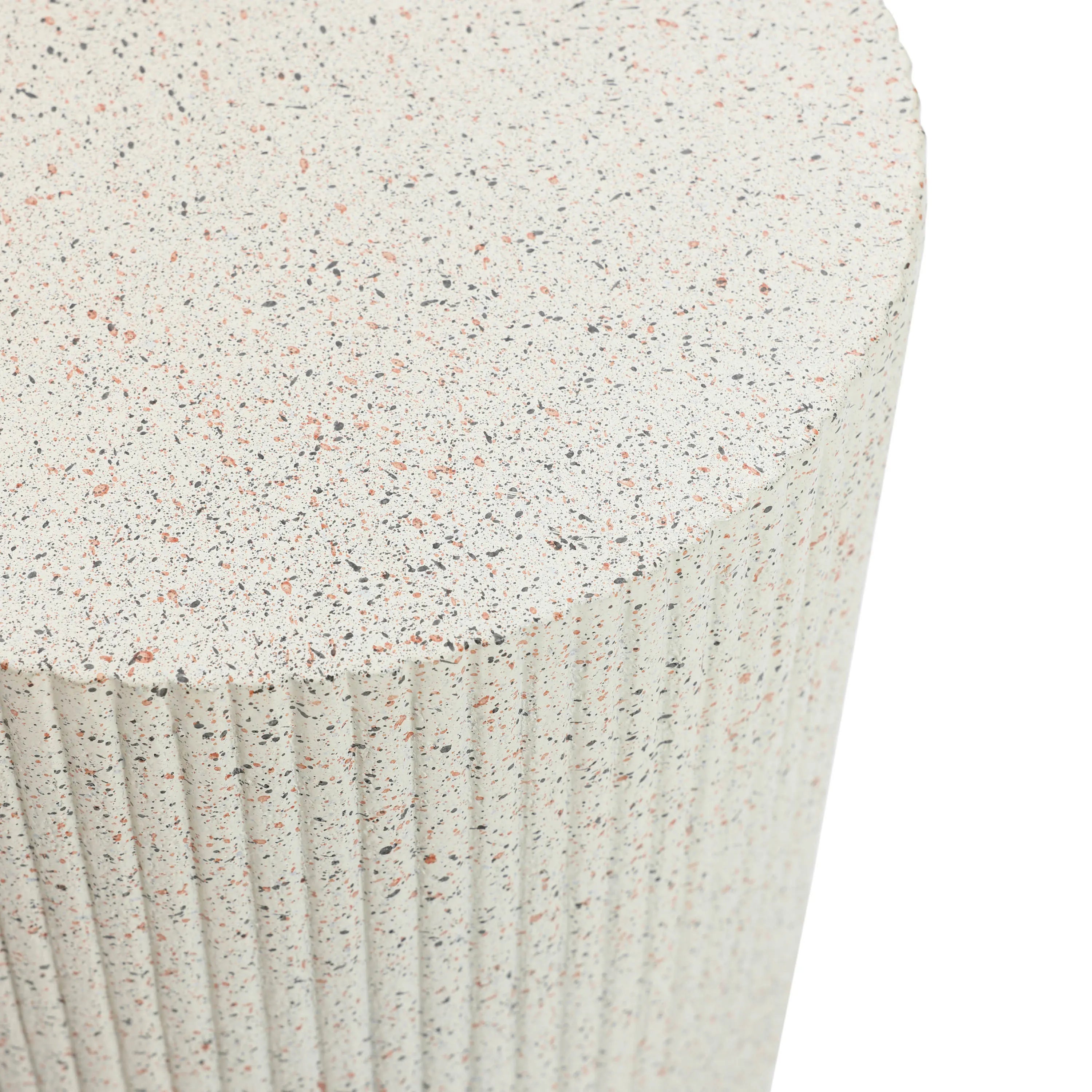 Close-up of a textured cylindrical surface reminiscent of an ivory white side table with vertical grooves and a speckled pattern in shades of beige, black, and pink.
