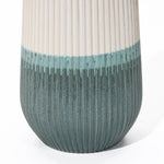 Close-up of a unique ceramic vase with a ribbed texture, transitioning from white at the top to teal at the bottom.