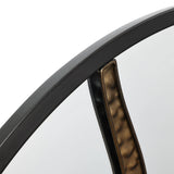Close-up of a round wall mirror with a black frame and an artistic design featuring a decorative metallic accent inside.