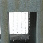 Close-up of water droplets falling in straight lines through a rectangular opening in a textured grey structure, creating a striking water fountain feature perfect for any outdoor living space.