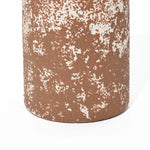 Close-up of a tall round ceramic vase with a textured surface in rusty brown and white, displaying a speckled pattern that exudes rustic charm.