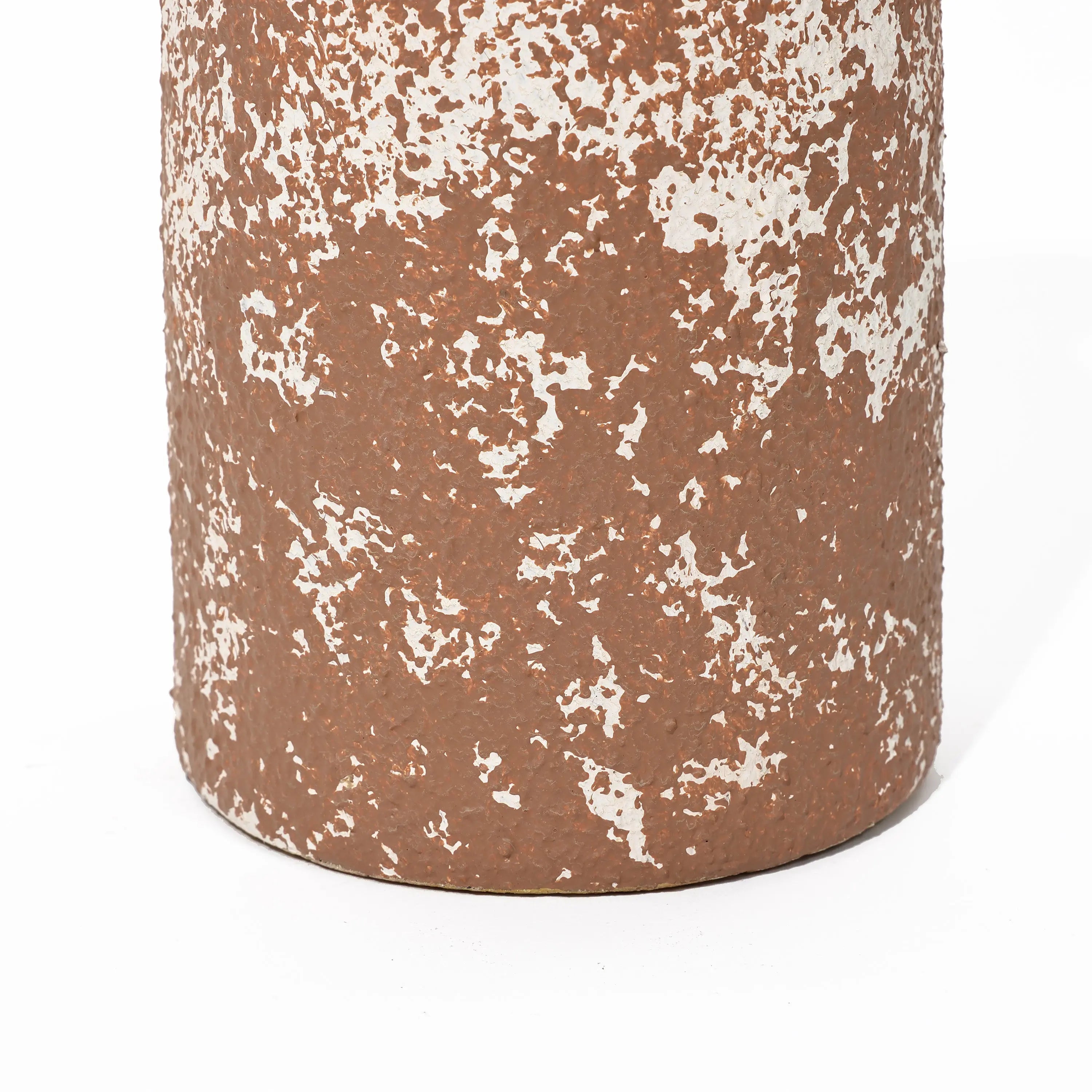 Close-up of a tall round ceramic vase with a textured surface in rusty brown and white, displaying a speckled pattern that exudes rustic charm.
