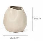 An ivory white, irregularly shaped ceramic vase serves as a charming accent piece with its measurements of 6.69 inches high and 6.89 inches in diameter.