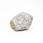 A textured, white ceramic vase with subtle gray and brown speckles, reminiscent of white marble texture, lies sideways on a pristine white background.