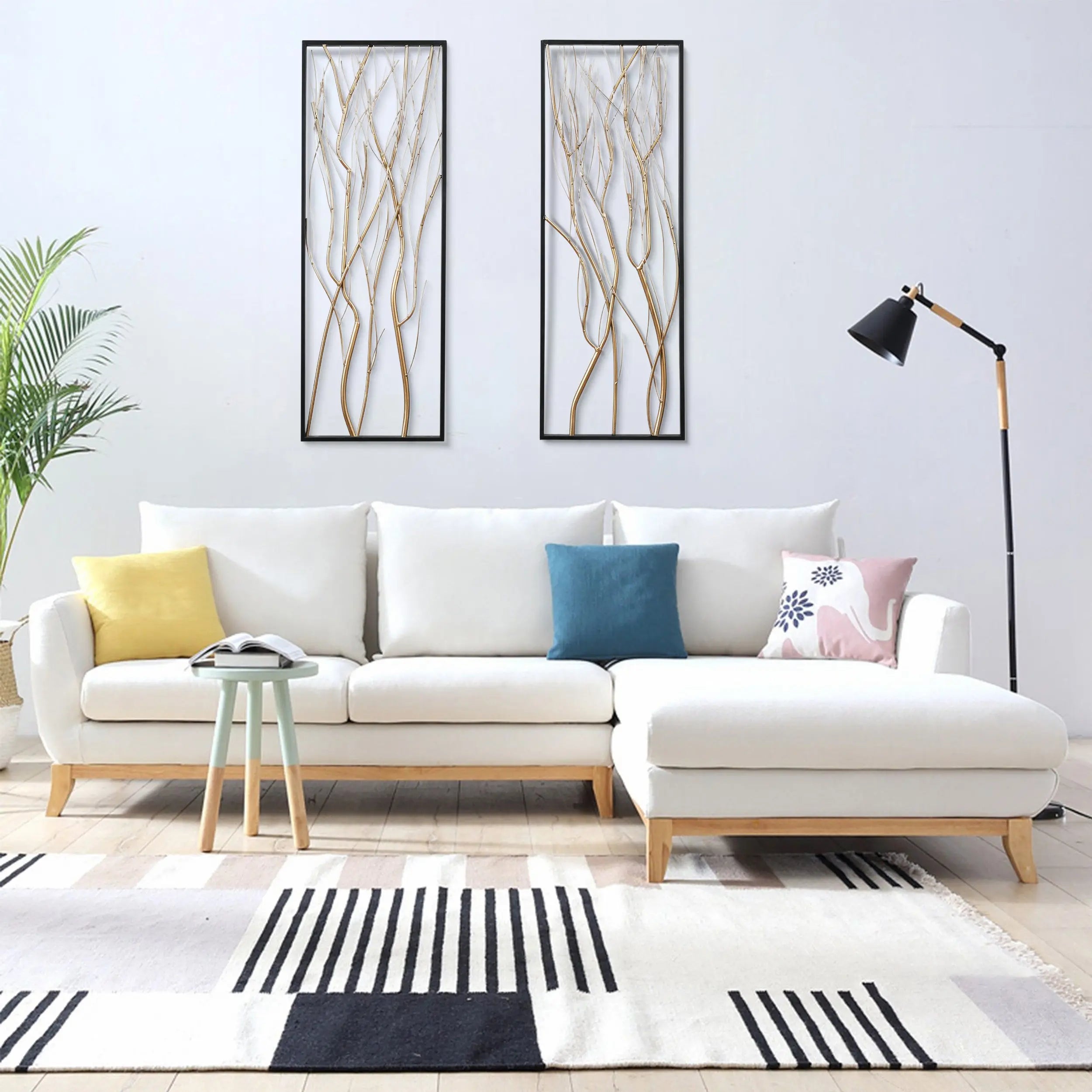 Modern living room with a white sectional sofa, colorful cushions, a floor lamp, a small side table, striking modern wall art as a focal point, a potted plant, and a striped rug on a light wood floor.