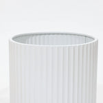 Close-up of a durable, vertically ribbed cylindrical object against a plain background, reminiscent of modern metal plant pots.