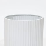 Close-up of a durable, vertically ribbed cylindrical object against a plain background, reminiscent of modern metal plant pots.