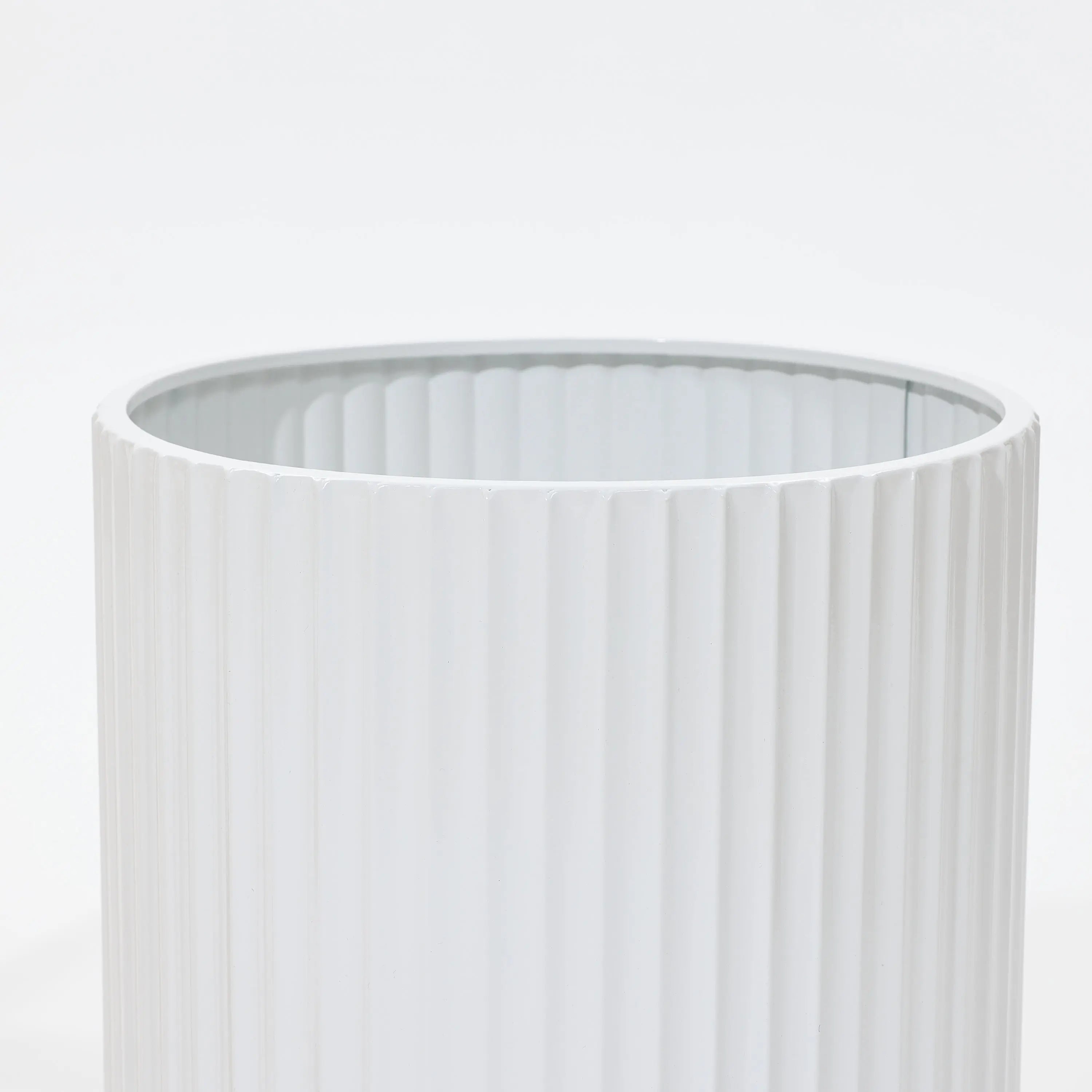 Close-up of a durable, vertically ribbed cylindrical object against a plain background, reminiscent of modern metal plant pots.