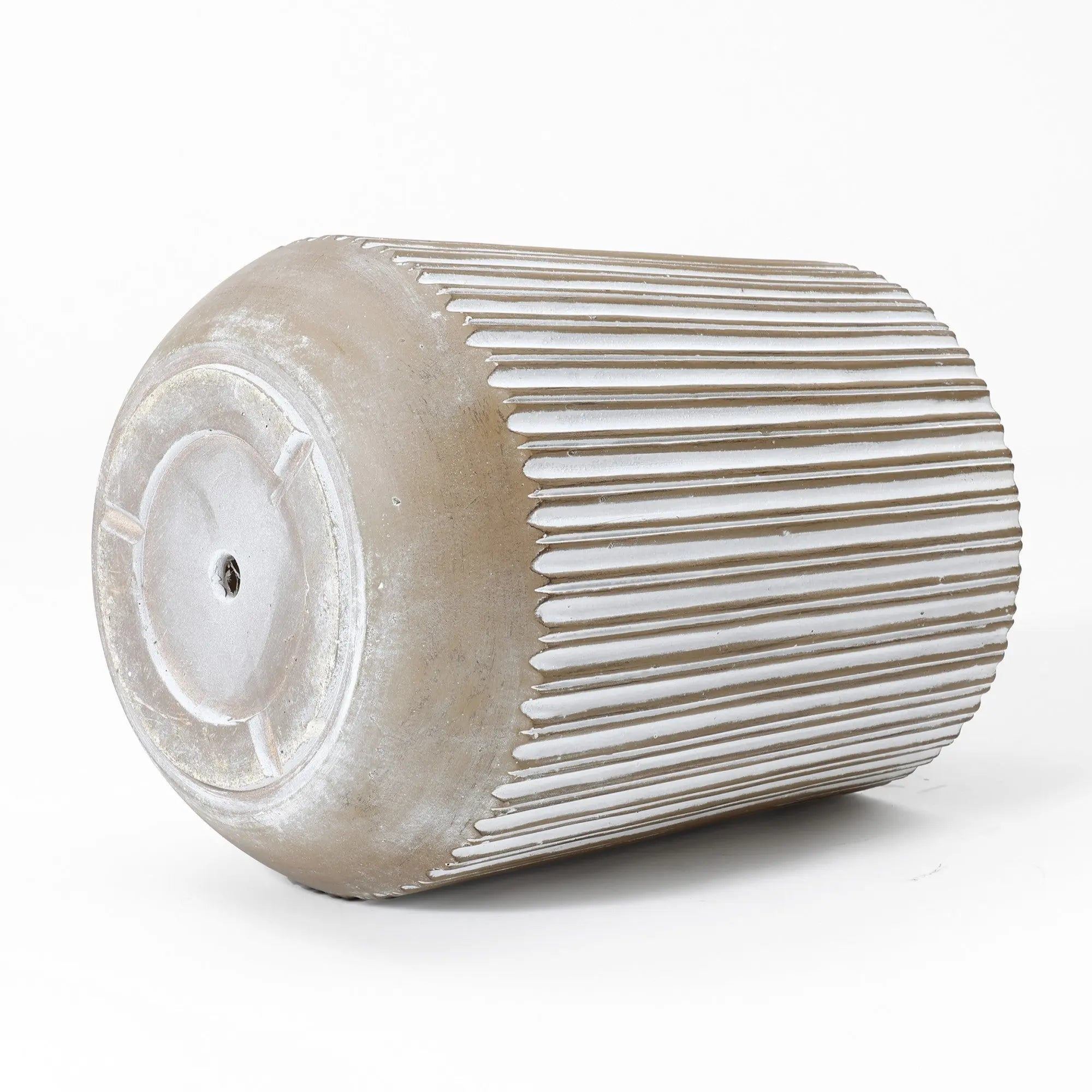 A large, cylindrical metal drum, resembling a weather-resistant planter, lies on its side against a plain white background, featuring a textured, ribbed surface.