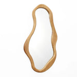 An abstract mirror with a wavy shape, set in a pine frame, exudes natural energy against a crisp white background.