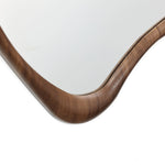 Close-up of a wooden frame corner of a wall mirror with smooth, curved edges against a white background, exuding minimalist design and Scandinavian charm.