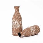 Two textured brown ceramic vases with white speckles, exuding rustic charm, sit against a white background. One stands upright while the other lies on its side, showcasing the beauty of handcrafted earthenware.