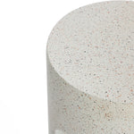 Close-up of a round, speckled stone surface, showing a textured finish with various small colored specks, ideal for an outdoor side table. The soft hues of ivory white cement blend seamlessly, offering a unique touch to your U-shaped design space.