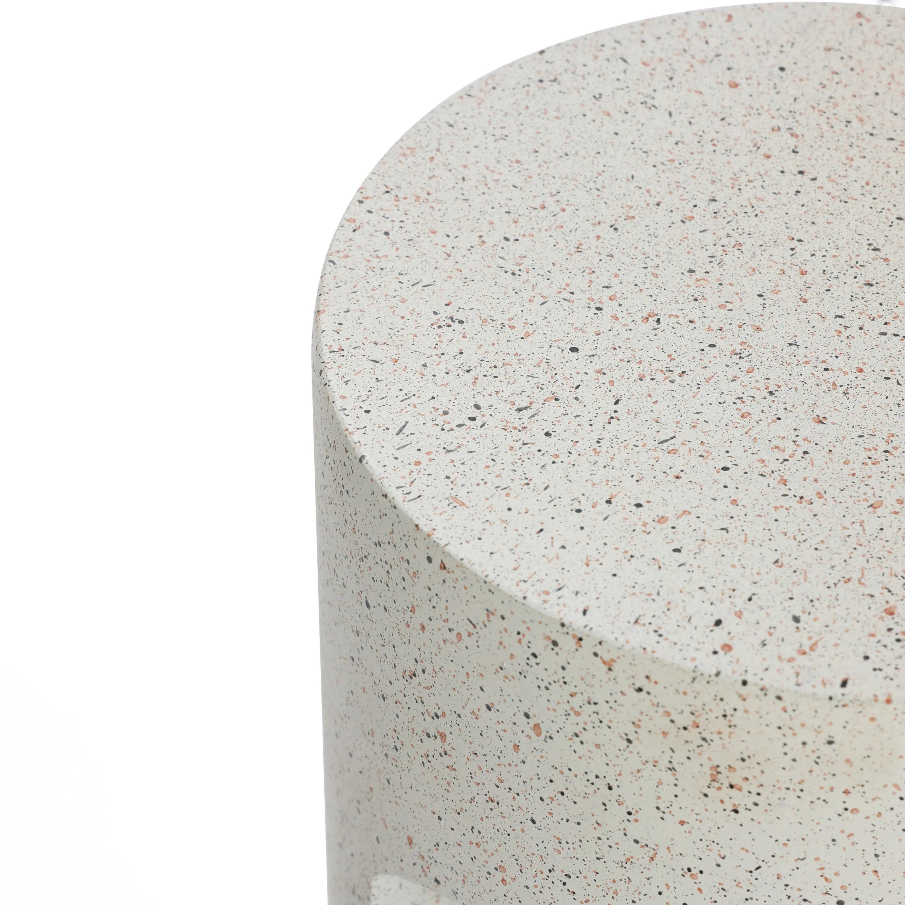 Close-up of a round, speckled stone surface, showing a textured finish with various small colored specks, ideal for an outdoor side table. The soft hues of ivory white cement blend seamlessly, offering a unique touch to your U-shaped design space.