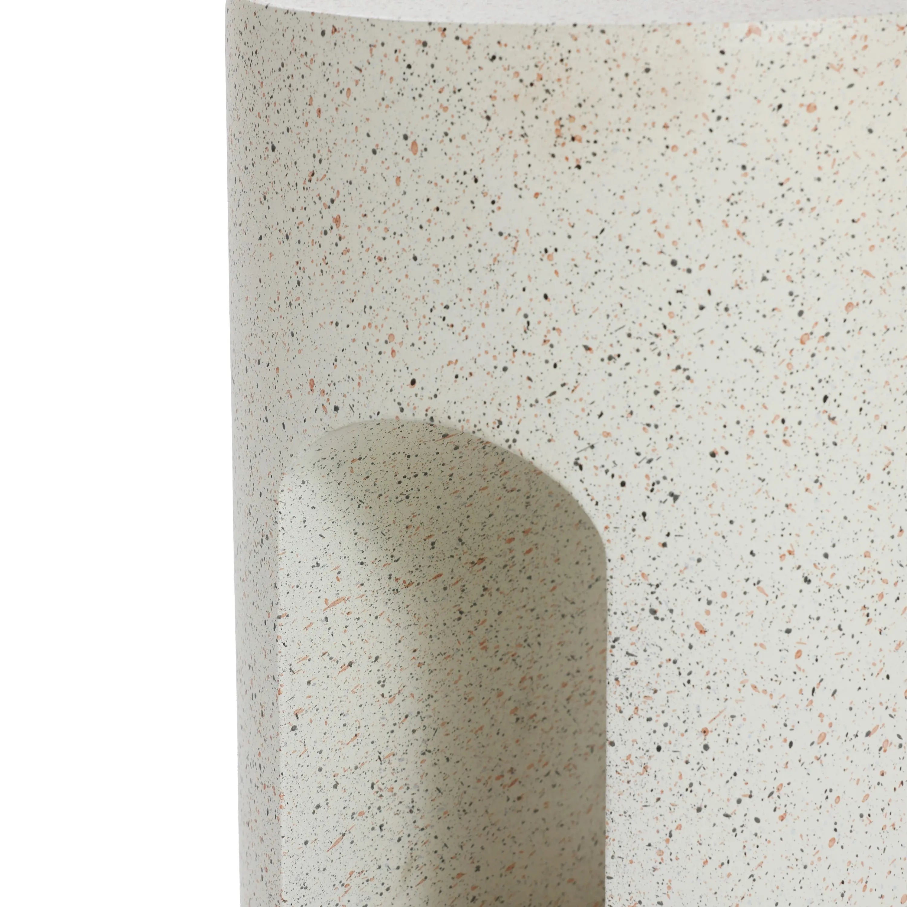 Close-up of a speckled, rounded outdoor side table with a U-shaped design, featuring a curved indentation and showcasing its textured ivory white cement surface.